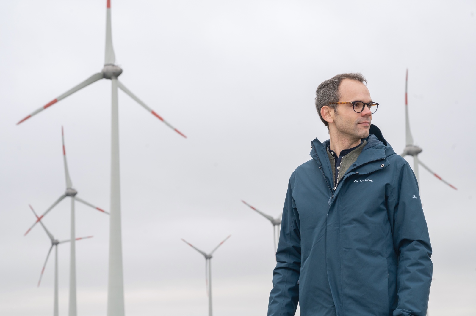 Fabian Faller, unabhängiger Energiewende-Berater, vor Windkraftanlagen in Schleswig-Holstein